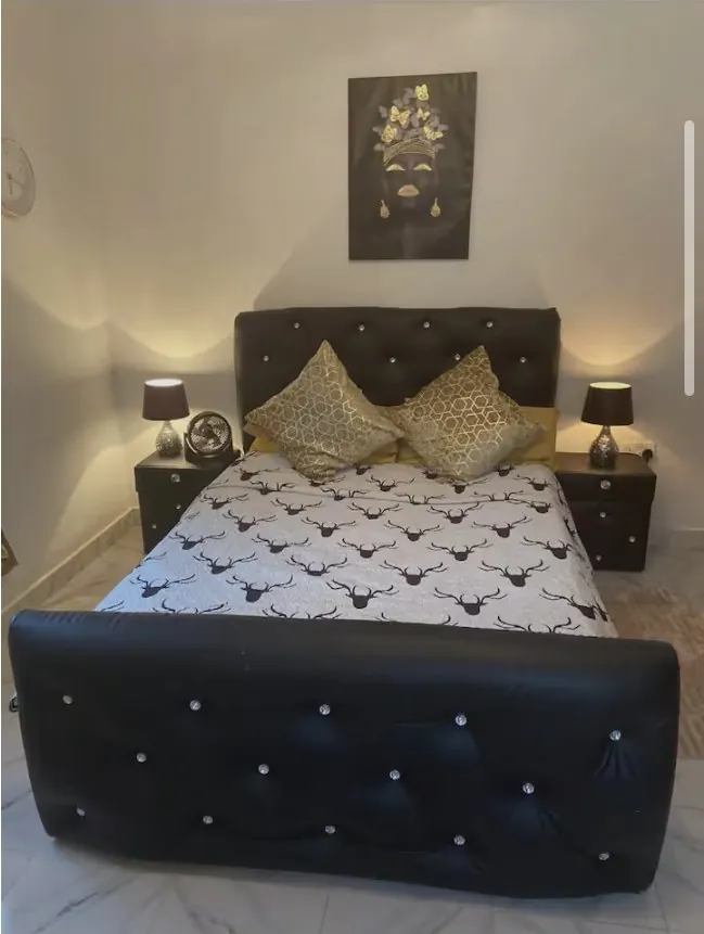 Bedroom 1: black tufted bed with gold accent pillows